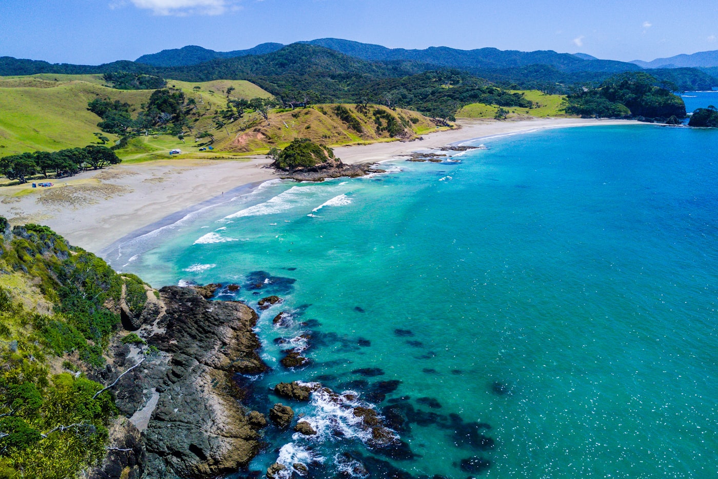 Aerial view of a New Zealand beach curving away beneath coastal hills