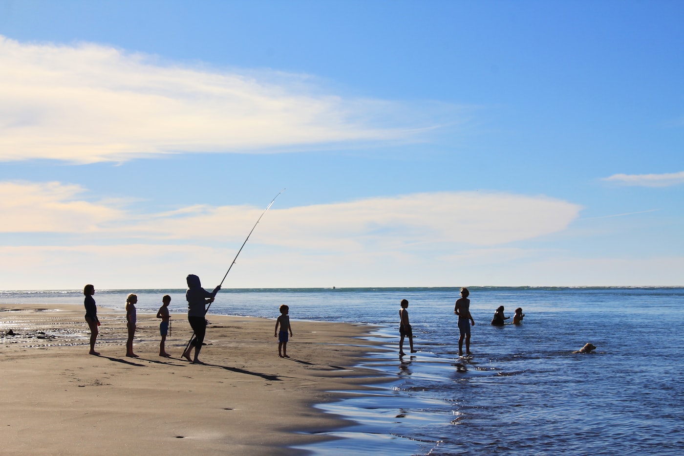 A family spread out along a wide New Zealand beach in summer
