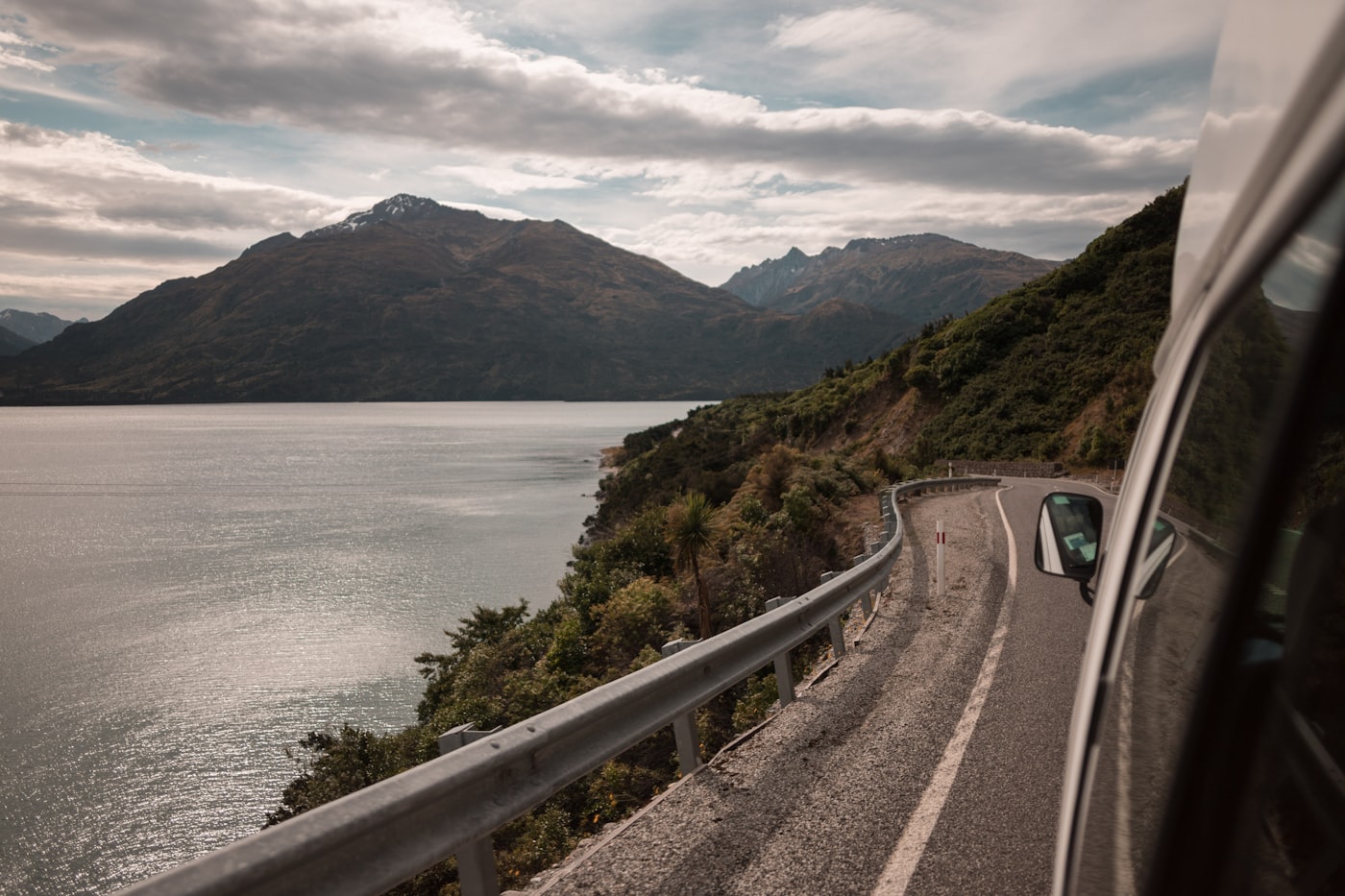 A vehicle on an empty New Zealand highway running toward the ranges